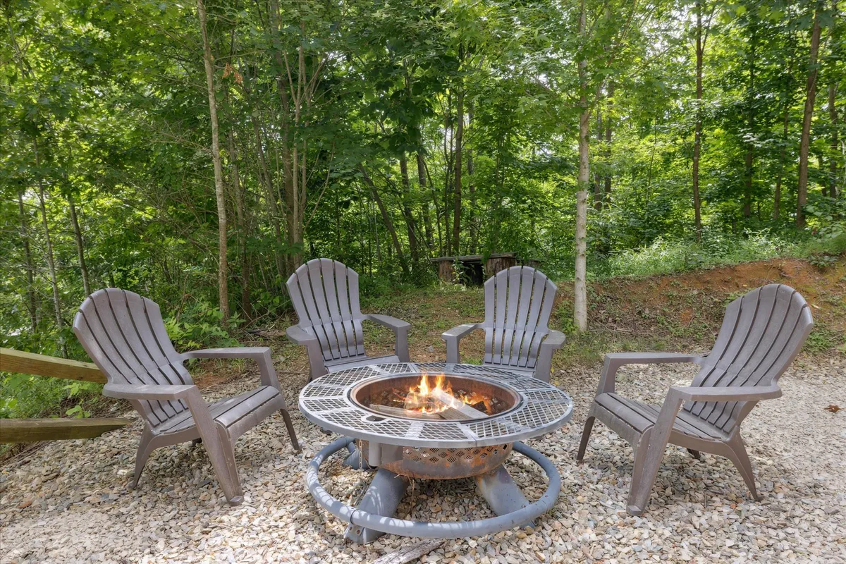 An inviting fire pit surrounded by Adirondack chairs sits nestled among lush greenery. The scene is cozy and perfect for evening gatherings, storytelling, or roasting marshmallows after a day of exploration.