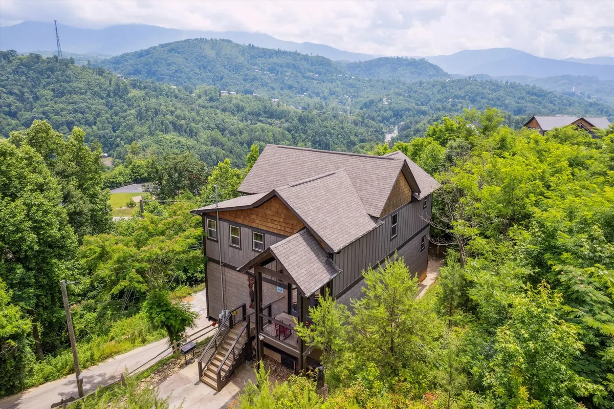 An exterior shot showcasing the cabin’s inviting structure nestled amid lush greenery and framed by distant mountain views. The setting evokes a sense of peaceful seclusion and easy access to hiking trails or outdoor adventures.