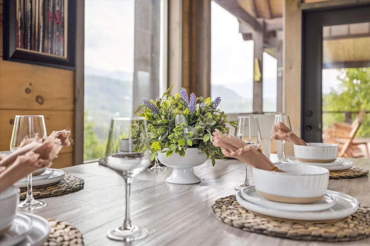 A cozy dining table set with a flower arrangement and elegant glassware. The warm ambiance invites guests to gather for family dinners, celebrations, and memorable shared experiences.